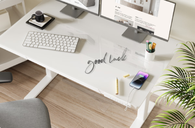 A modern standing desk with a monitor, keyboard, and office supplies.